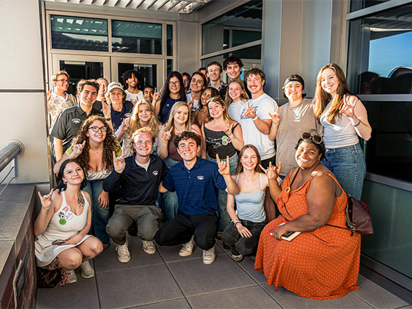 Group of ASUN students pose for a group picture with the wolf salute.