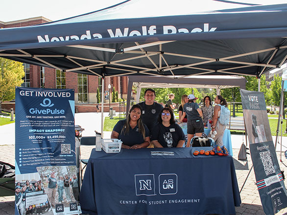 Students working a table underneath an easy-up inviting others to "Get Involved"