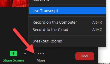 Screen clipping of the Zoom interface with an arrow pointing at the activeted More menu. The menu includes the item: Live Transcript.
