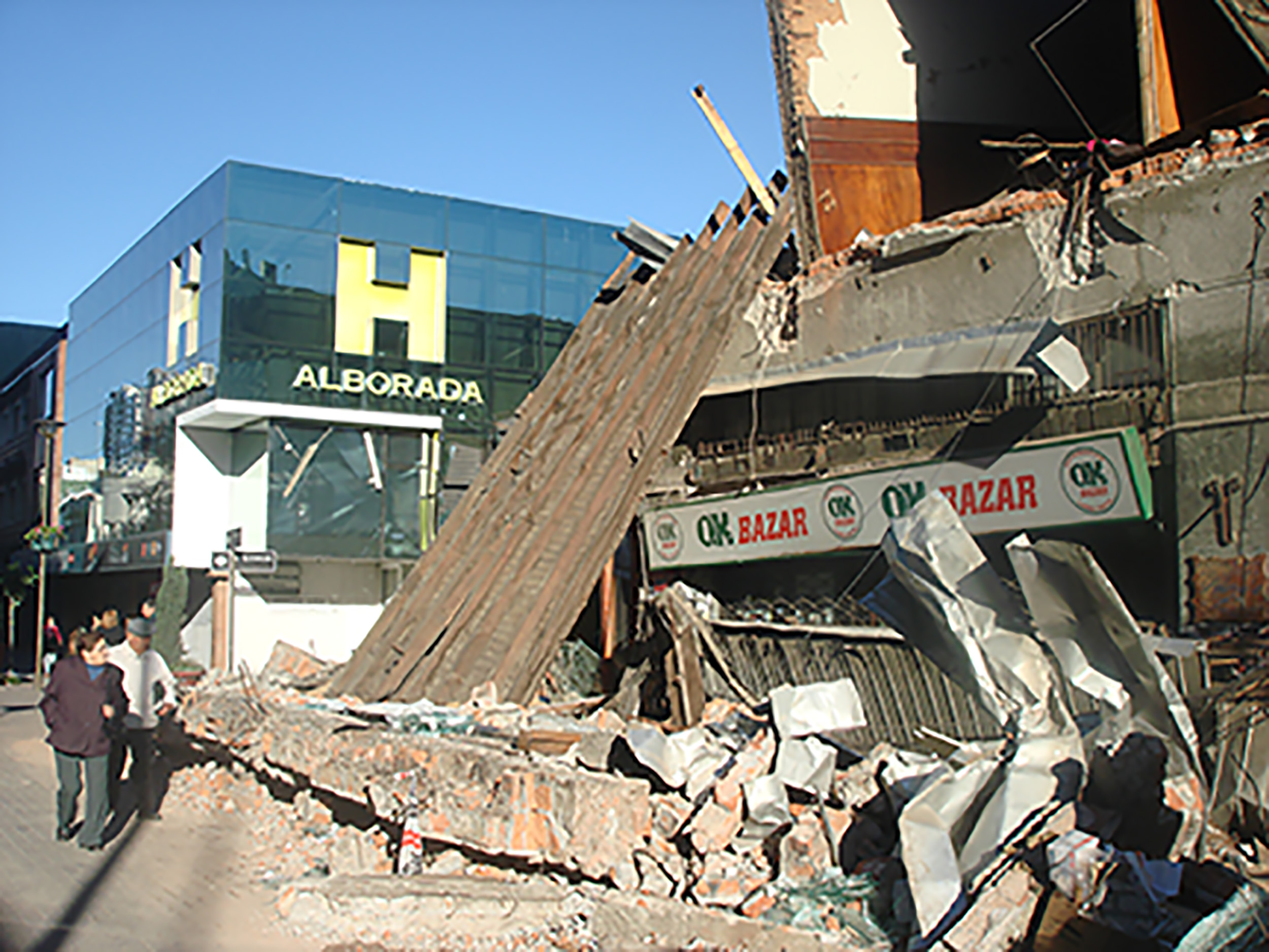 upright building next to fallen building in earthquake