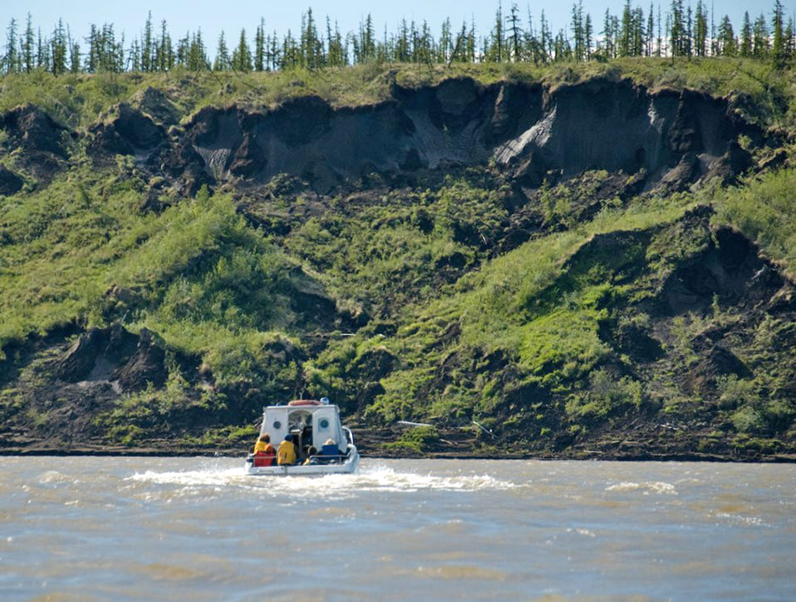 boat heading to thawing tundra cliffs
