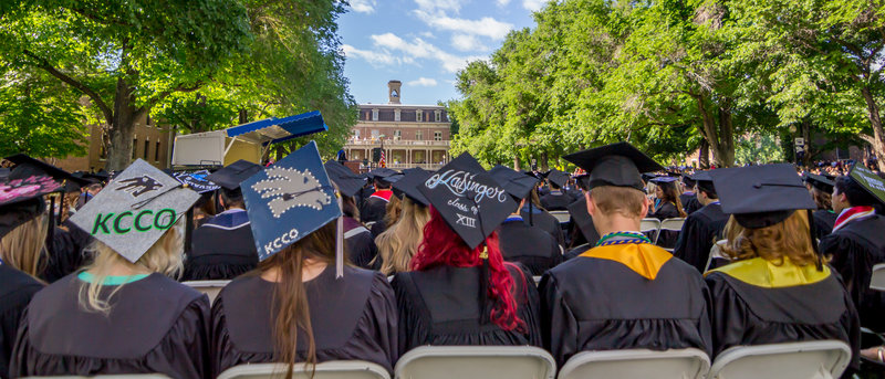 Backs of 5 graduates at spring commencement in the quad