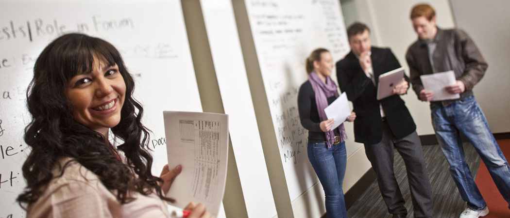 A presenter stands before judges during a presentation.