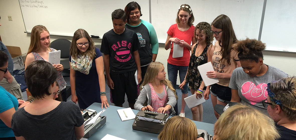 Students gathered around a table with typewriters