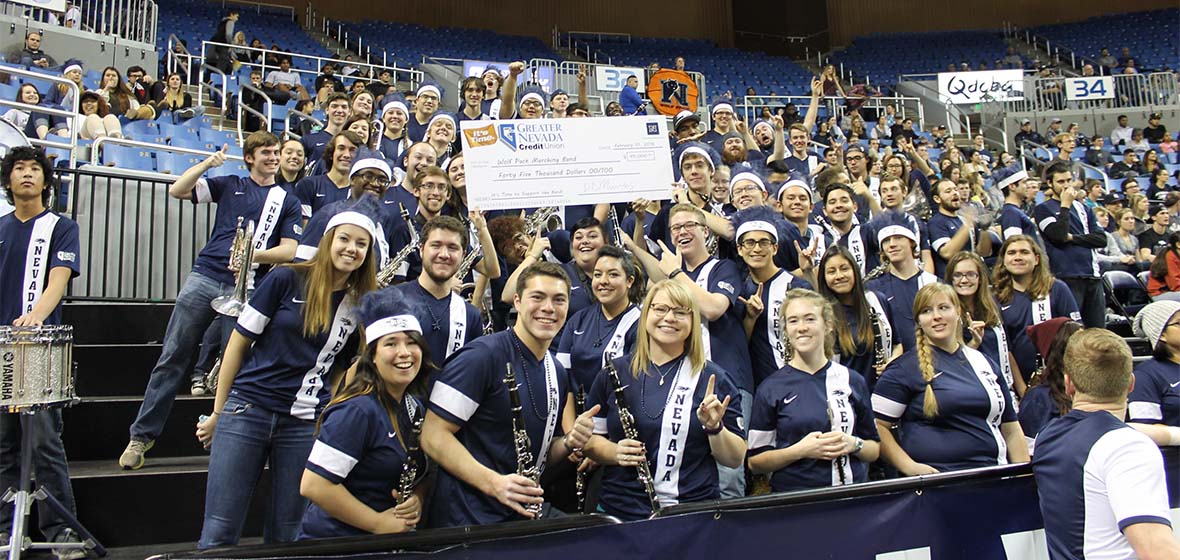 The Pride of the Sierra Marching Band filling the stands in Wolf Pack gear accepts giant gift check from Greater Nevada Credit Union.