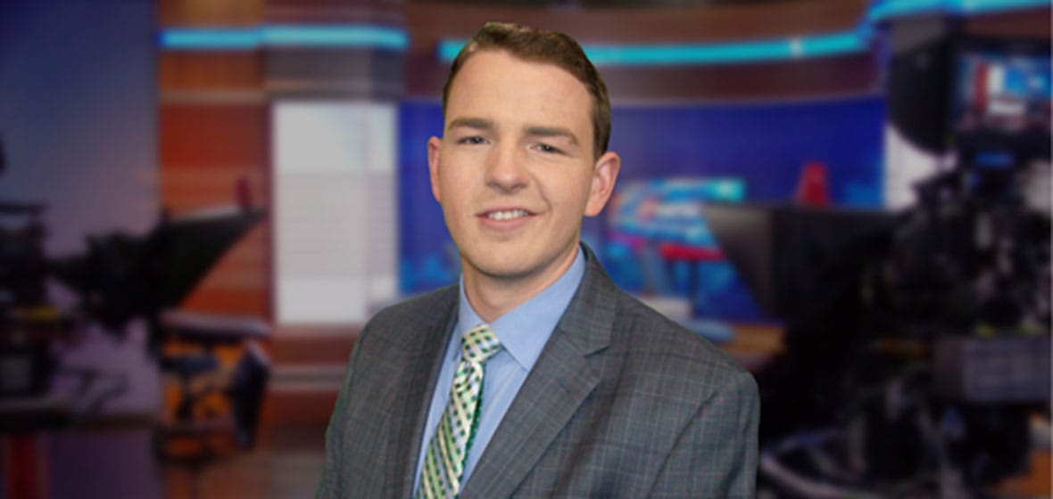 Man poses inside a news studio.