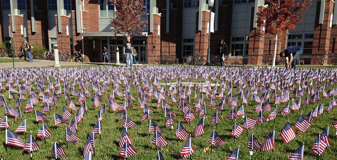 Mini flags planted in grass in front of Joe Crowley Student Union