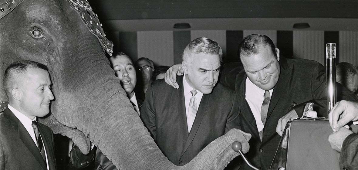 John Ascuaga, Bertha the Elephant, Lorne Green and Dan Blocker looking at a slot machine in John Ascuaga's Nugget as Berth's truck pulls the slot handle. 