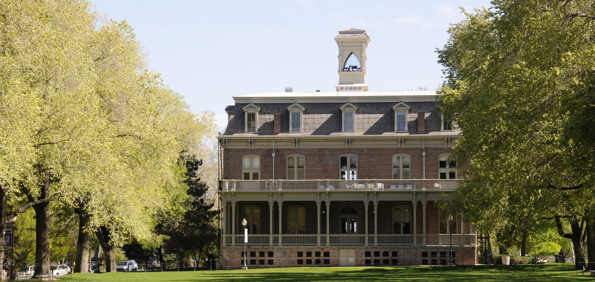 The north side of Morrill Hall surrounded by trees, with the Quad lawn in the foreground