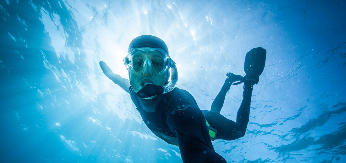 Photographer in wet suit takes photos under water in Lake Tahoe