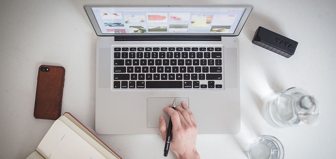 A hand can be seen typing on a laptop 