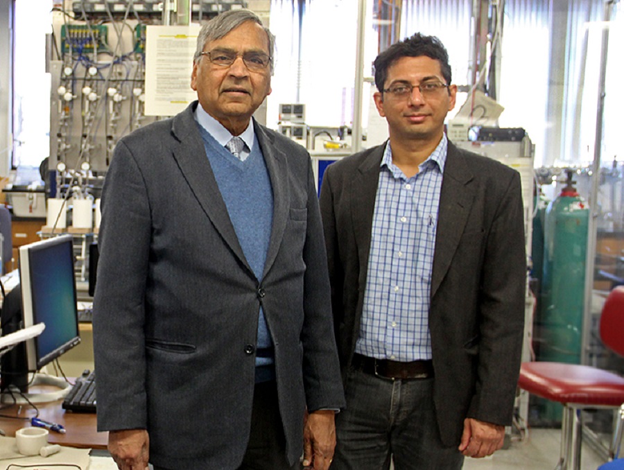 Two professors standing behind machines in a lab.