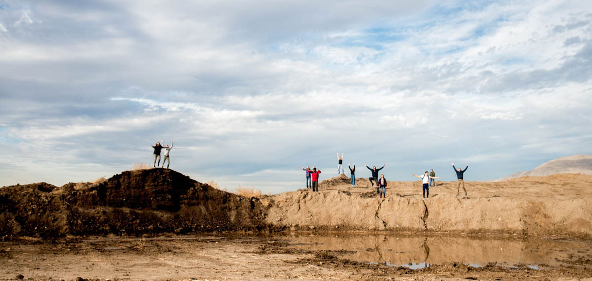 Students pose for a photo on top of a large dirt hill