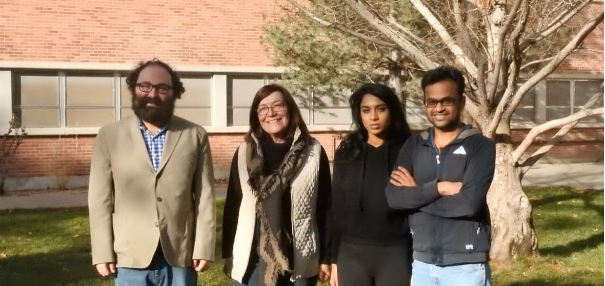 Two professors and two students stand infront of a tree.