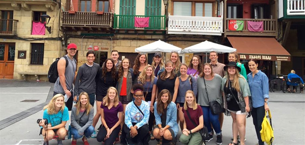 Happy USAC students standing in front of a colorful international background