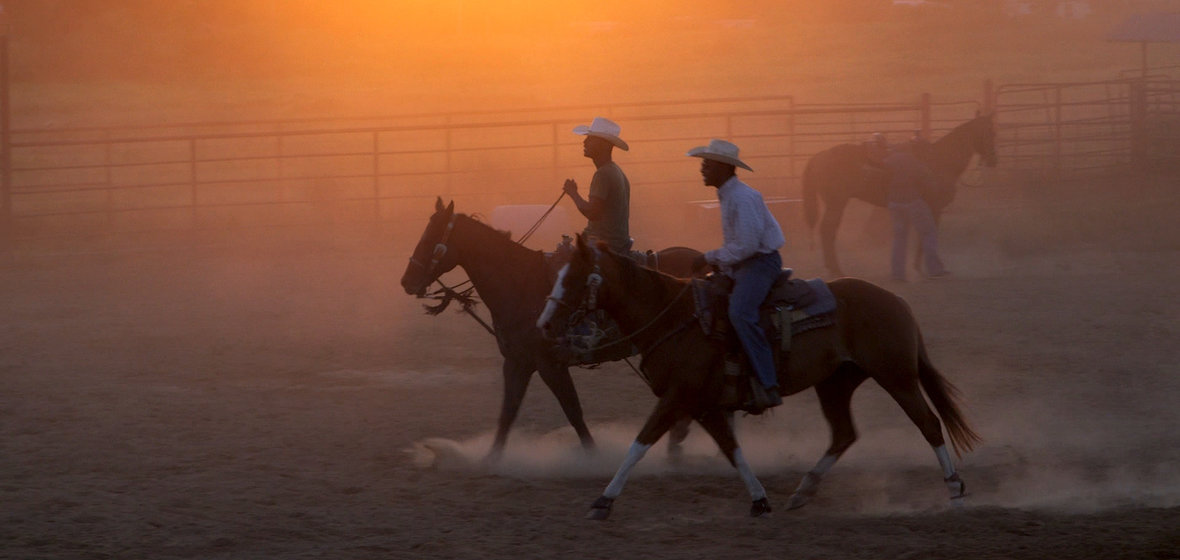 Spencer Nero and Darius Ford ride horses at sunset