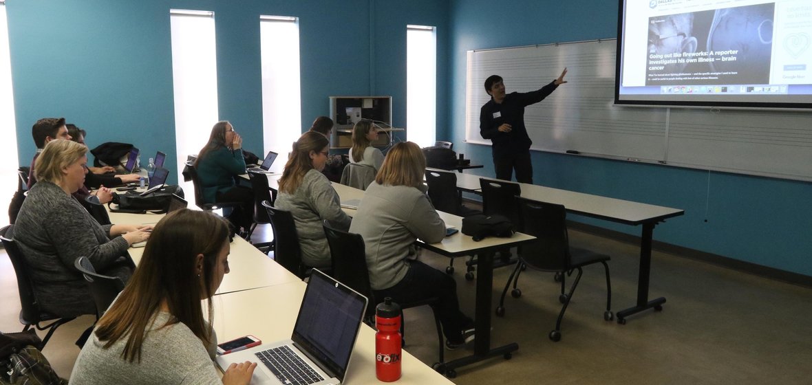 Digital storytelling workshop in classroom with presenter pointing to board and large monitor