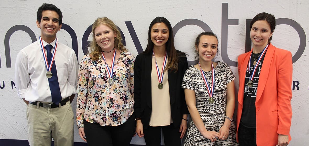 A group of students pose for a photo, all wearing medals. 