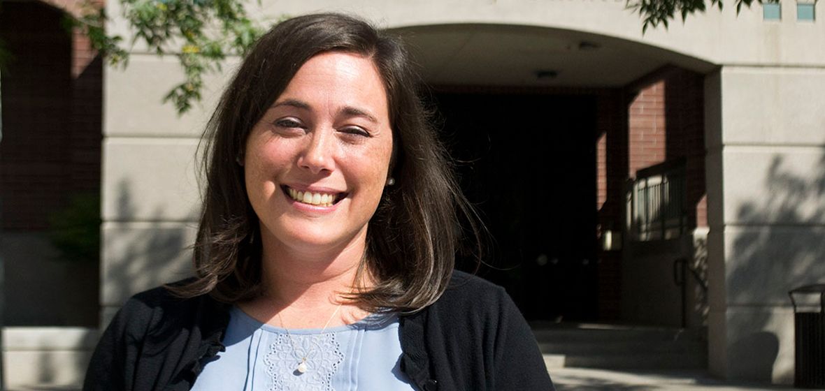 A woman outside a building smiles for the camera. 