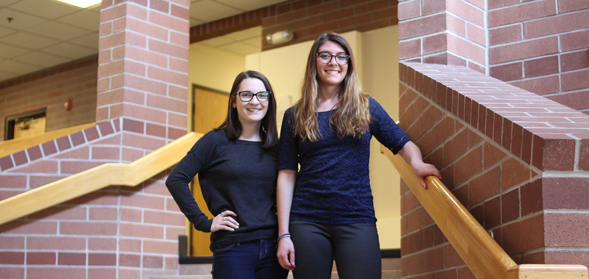 Madeline Purdue (left) and Andrea Heerdt (right) pose for a photo in the Reynolds School of Journalism's atrium. 