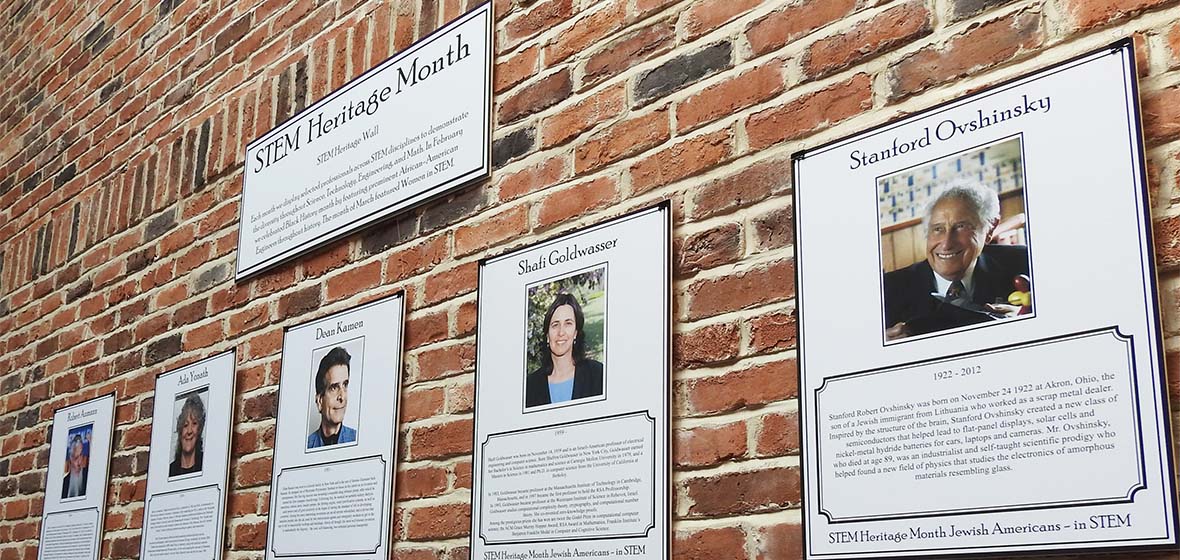 Five pictures on a brick wall indicating the STEM Heritage Exhibit.