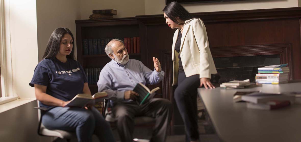 A professor, middle, sitting, instructing two students