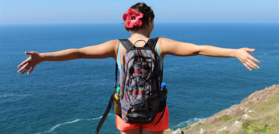 USAC student standing on beautiful bluff overlooking a beach.