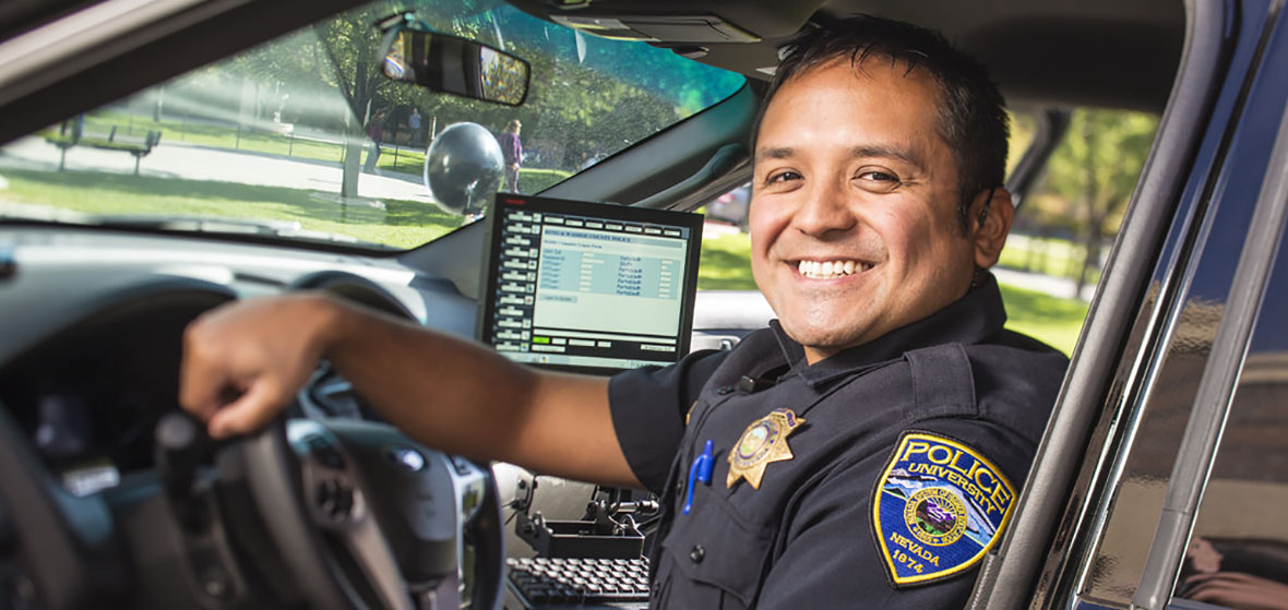 University police smiles from inside his police car. 