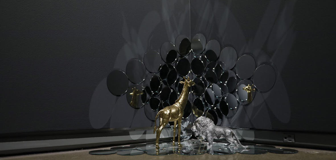 "Self existences" by Mahedi Anjuman. A mixed sculpture piece with golden girafe and silver lion on mirrored background.
