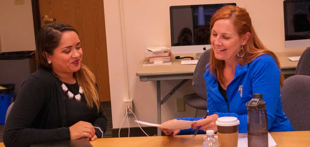 Two women sit a a table. 