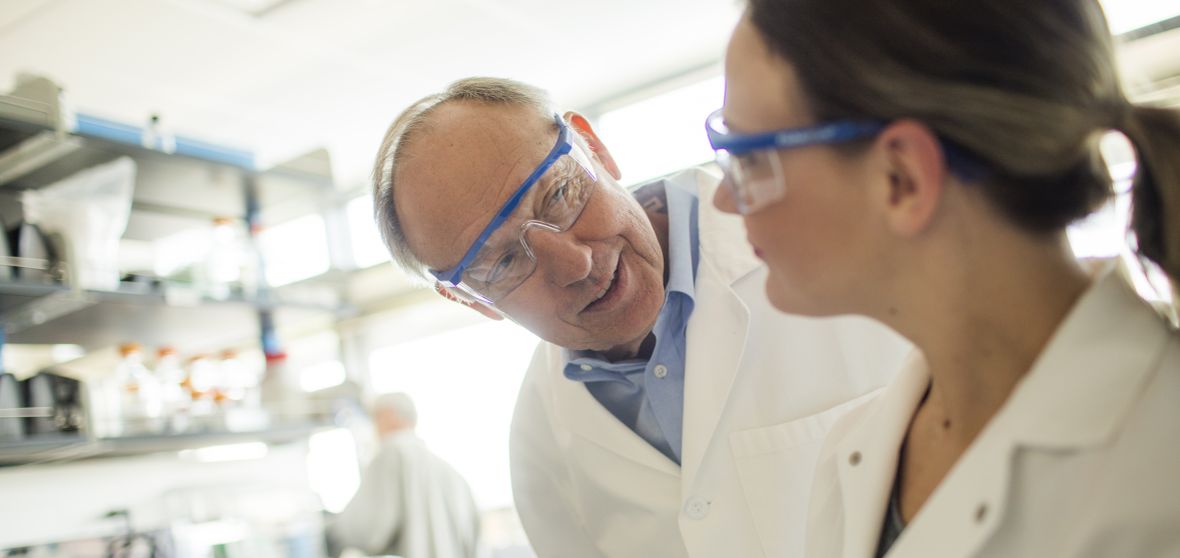 Professor Tom Kozel talks with a colleague in a laboratory.