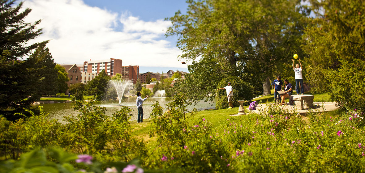 Students throwing frisbee in front of Manzanita Lake with fountain in the middle