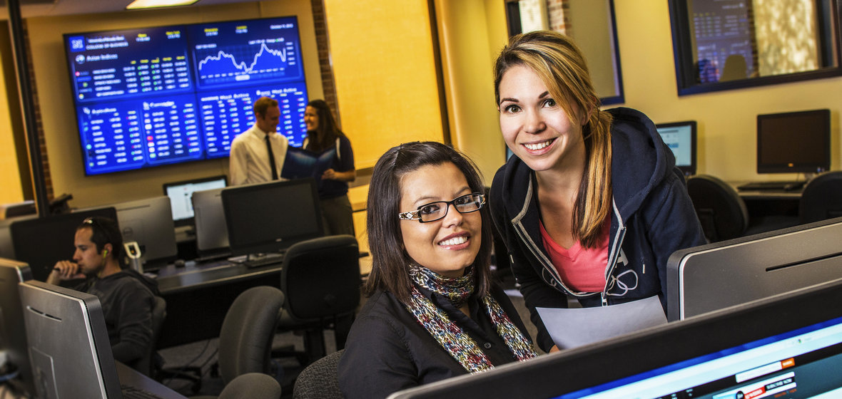 Business students in a computer lab with financial data in the background