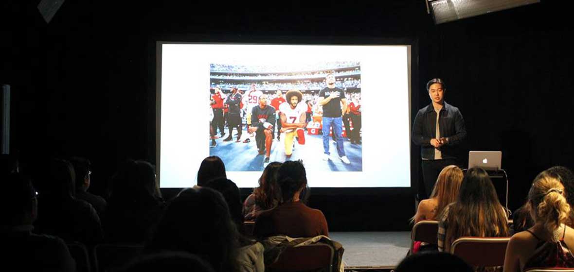 A man stands in front of a small crowd of students. 