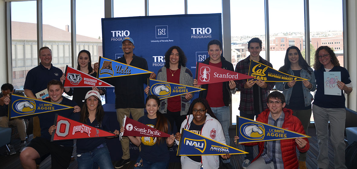 11 McNair Scholars holding their pennants from their chosen graduate schools with Perrry Fittrer on the far left. 
