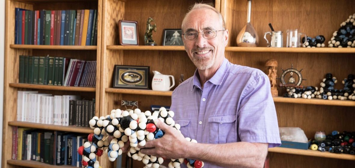 Professor holds a large-scale model of a molecule.