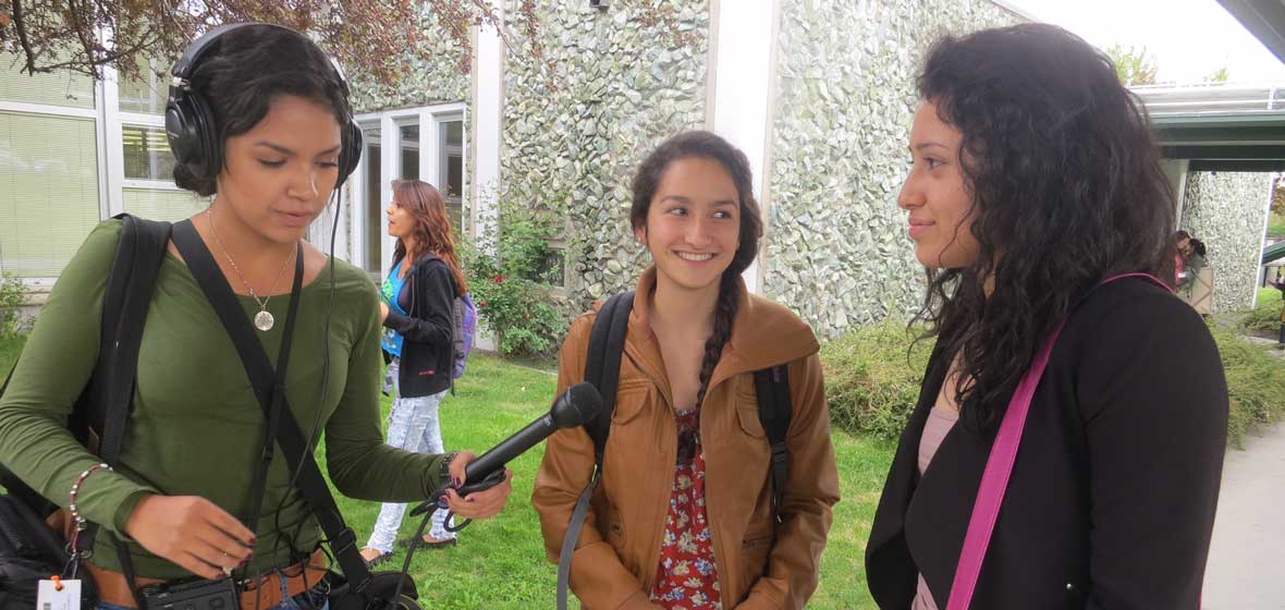 A woman records an interview with two other women. 