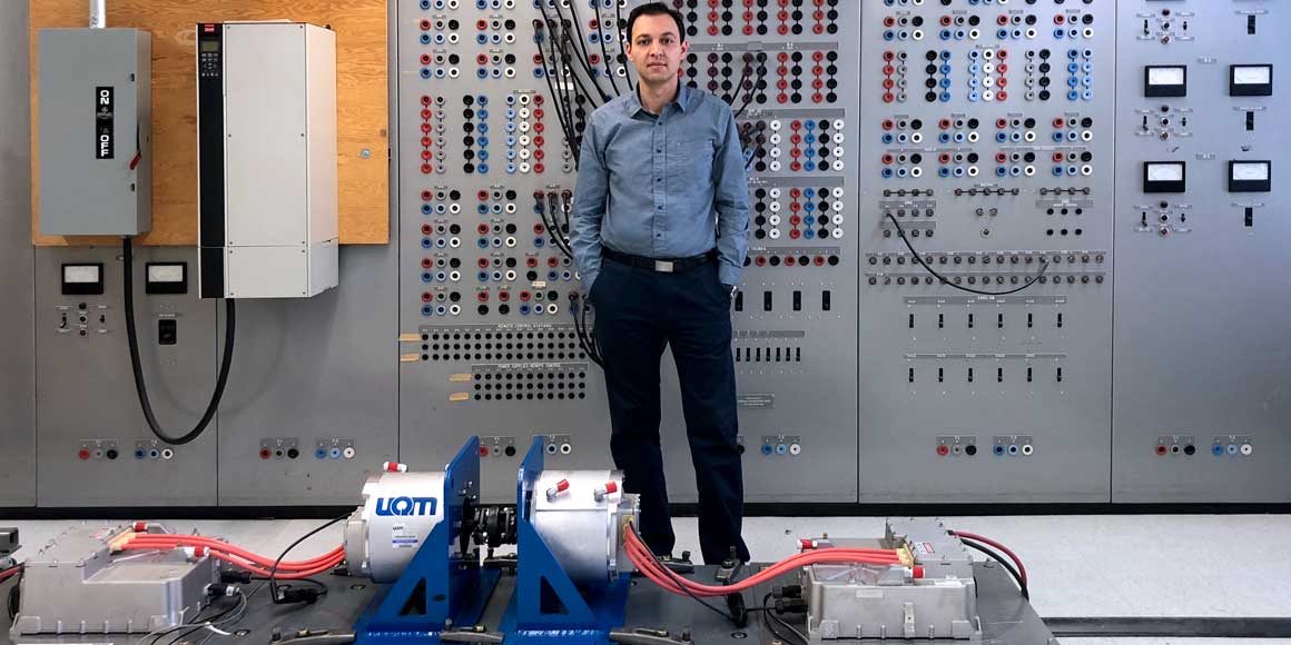 A man stands in front of motors in a laboratory. 