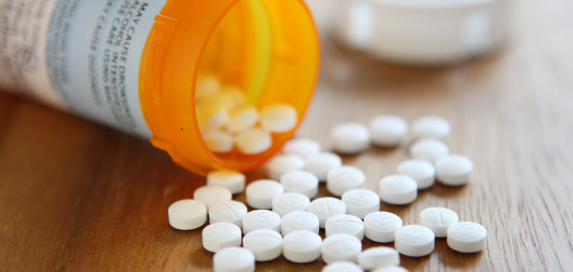 Prescription bottle open on table with pills spilling out