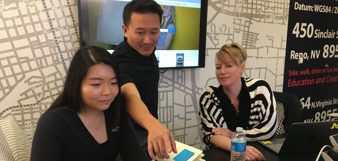 Three individuals look at computer screen and are in discussion