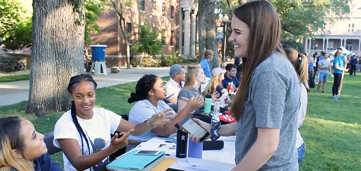 A young woman stands in front of a table of students