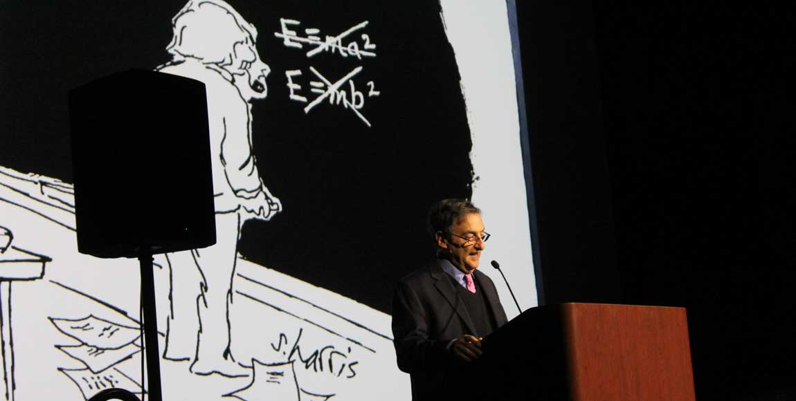 Man lectures at a podium with a screen behind him.