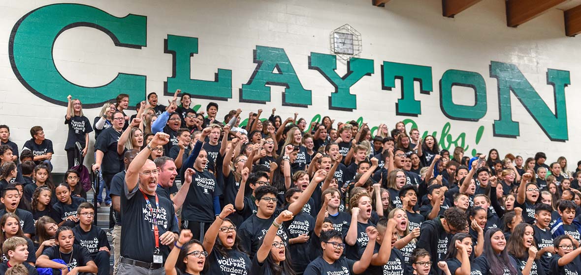 Clayton Middle School students stand and cheer in the bleachers 