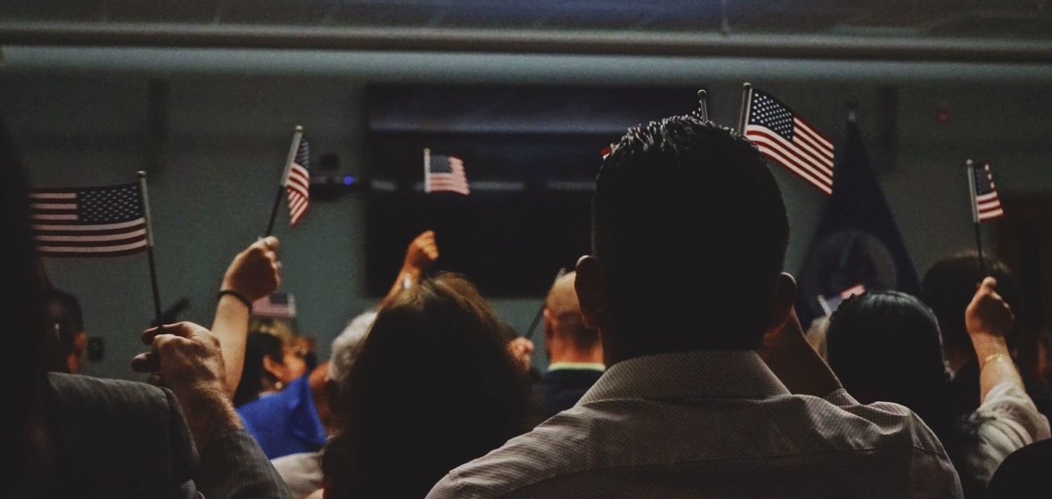 A group of people in a classroom holding up small American flags