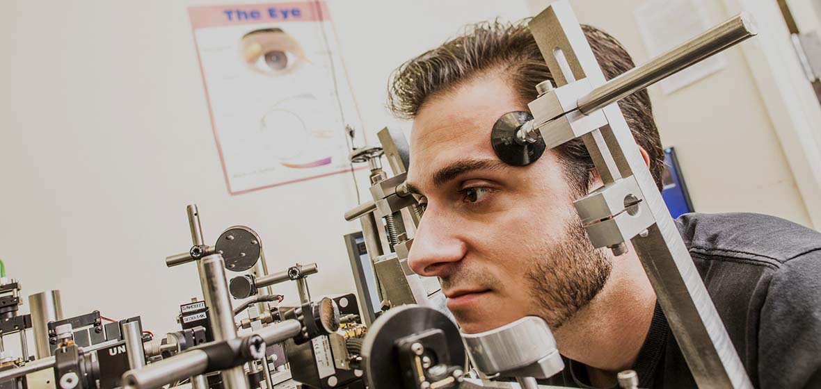 A student rests his head in an Adaptive Optics system