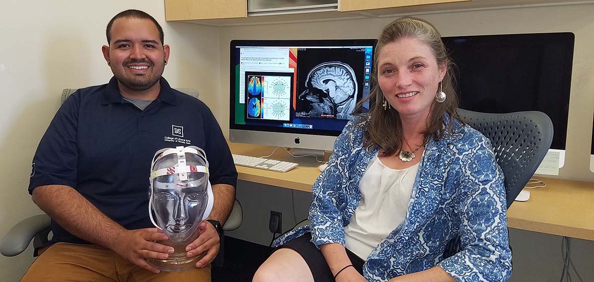 Hector Arciniega and Marian Berryhill are seated as a computer work station; Hector holds a clear 3-D representation of a human head.