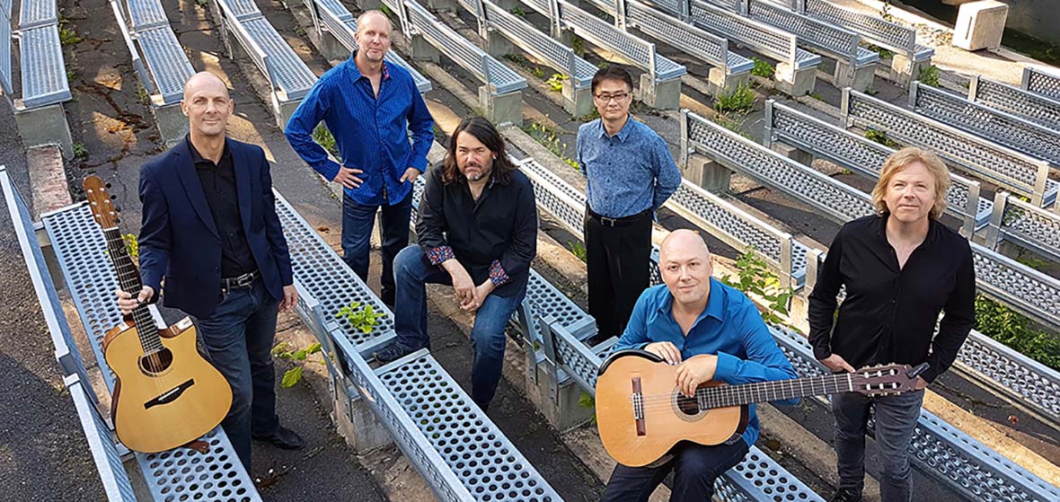 California Guitar Trio and Montreal Guitar Trio pose with instruments on seats of an outdoor amphitheater