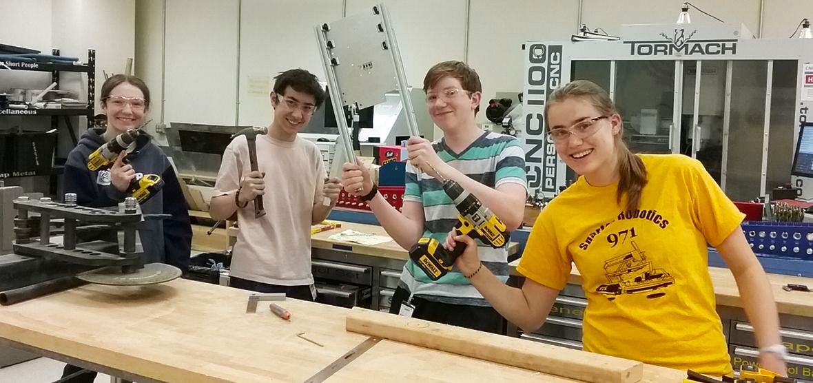 Four high school students with hand-held tools in a makerspace