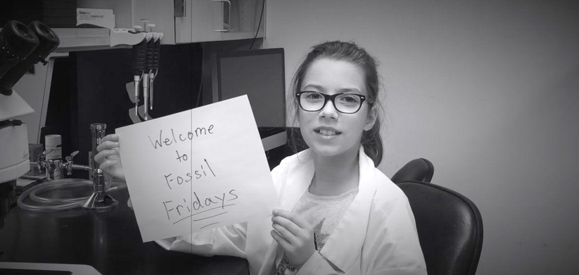 Girl holding sign that reads "Welcome to Fossil Fridays"