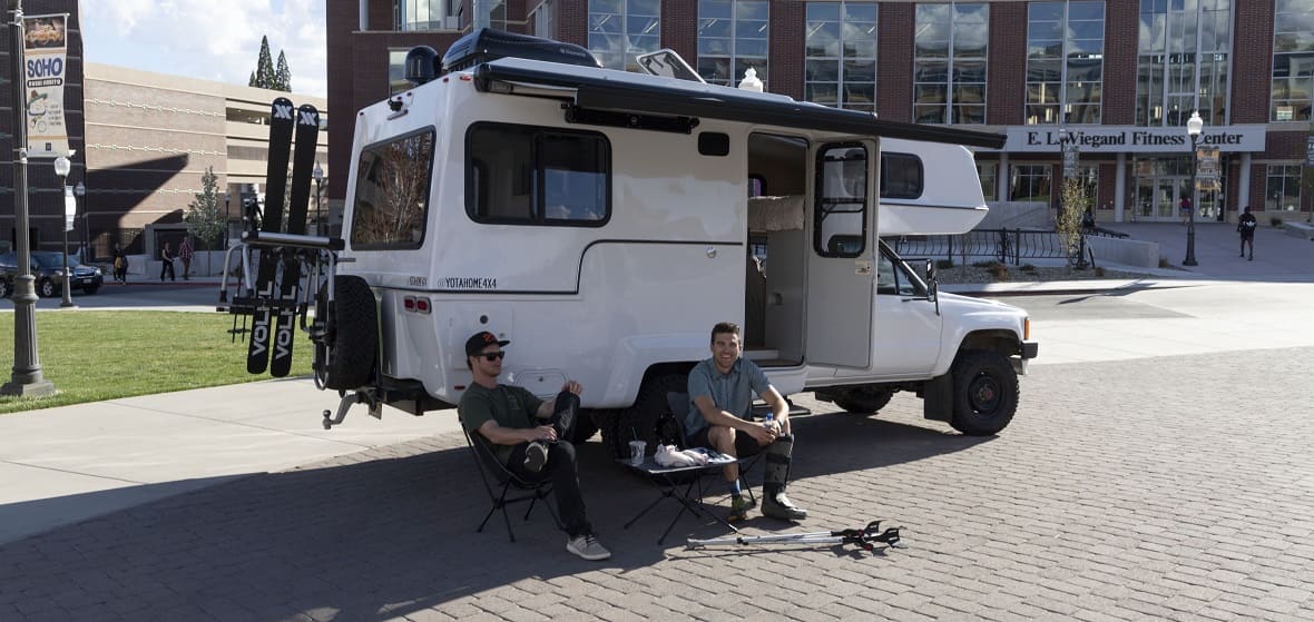 Two students sit in front of a Sturn Designs concept vehicle outside of the Joe Crowley Student Union. 